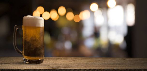 Canna di birra con bicchiere di birra sul tavolo su sfondo di legno - Foto, immagini