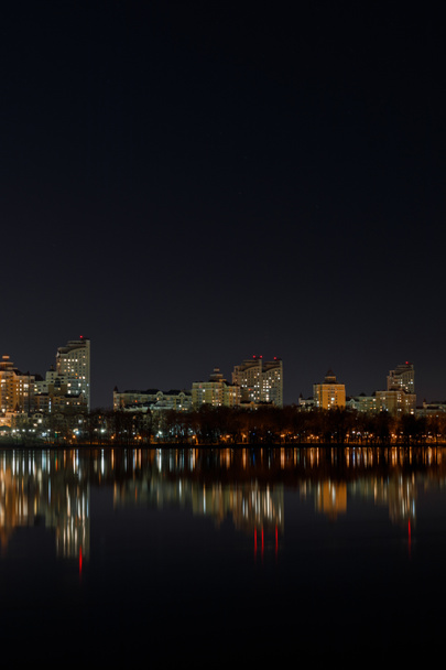edificios iluminados con reflexión sobre el agua por la noche
 - Foto, imagen