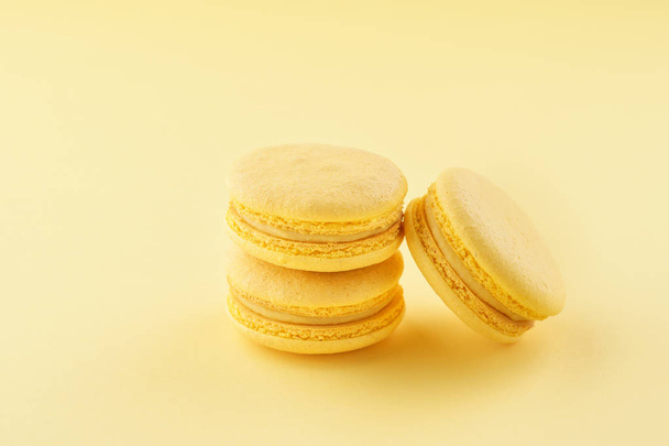 Stack of yellow macarons on same color background. - Zdjęcie, obraz