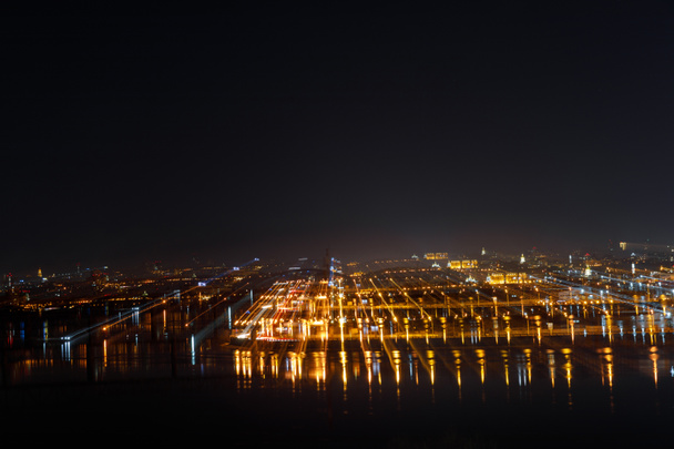 ilmakuva rauhallisesta kaupunkimaisemasta valaistuilla rakennuksilla yöllä
 - Valokuva, kuva