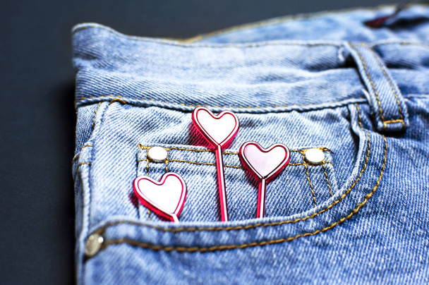 Blauwe jeans en rode harten van Pocket op zwarte achtergrond bovenaanzicht platte lag. Detail van mooie blauwe jeans. Jeans textuur of denim achtergrond. Trend kleding. Mode, kleding concept, love to jeans. - Foto, afbeelding