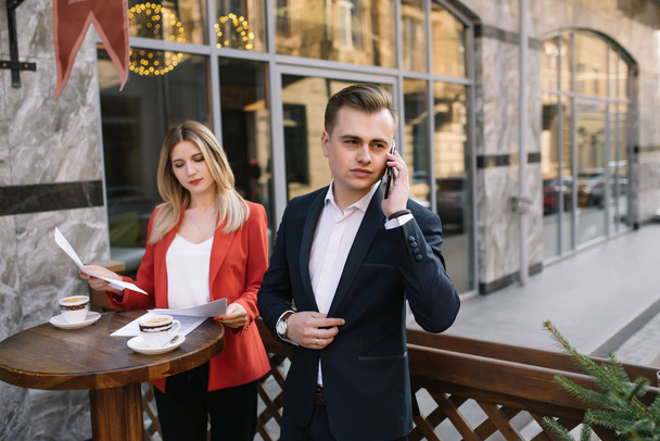 Business Woman and Business Man Use Smartphone and Talk on the Busy Big City Street. Both Look Exquisitely Stylish. - Photo, image