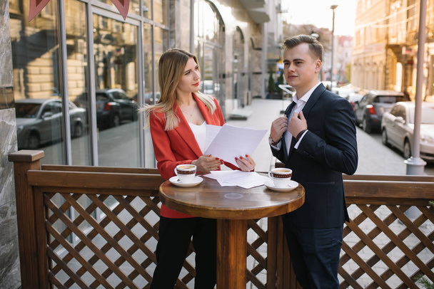 Preparation for meeting. Two young business people standing outside on the city street holding documents looking at each other smiling happy bottom view close-up - Zdjęcie, obraz