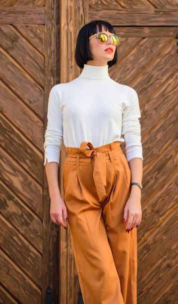 Fashion and style concept. Woman fashionable brunette stand outdoors wooden background. Girl with makeup posing in fashionable clothes. Fashionable outfit slim tall lady. Woman walk in elegant outfit - Fotó, kép