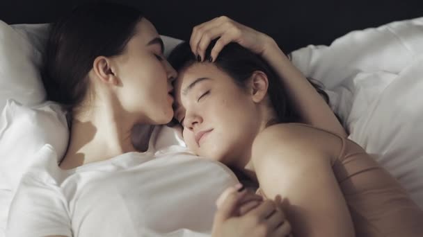 Lesbian couple embracing in the bed at home. One girl kisses another girl when she is sleeping Slow motion. Lifestyle, LGBT concept - Video