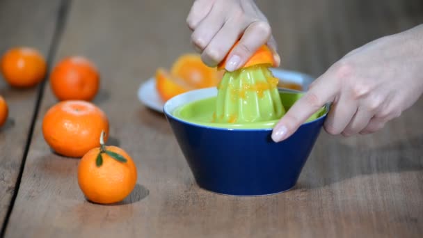 The girl squeezes the juice out of half an tangerine. - Footage, Video