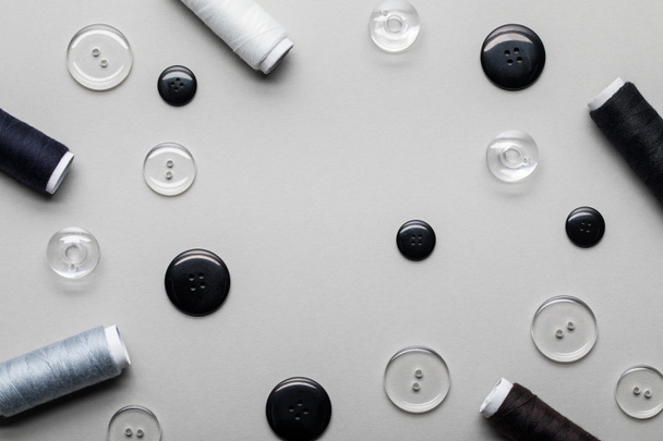 pohled na oděvní tlačítka a svitky vlákna izolované na šedé - Fotografie, Obrázek