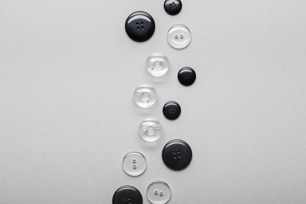 Widok z góry na ułożone czarne i przezroczyste guziki odzieżowe izolowane na szaro z kopią miejsca - Zdjęcie, obraz