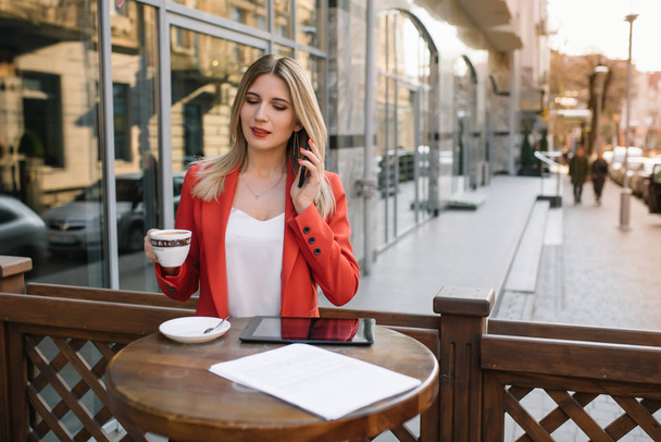 Businesswoman taking a coffee break and using smartphone. - Фото, зображення