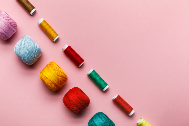 vue de dessus de boules de tricot colorées et bobines de fil sur rose avec espace de copie
 - Photo, image