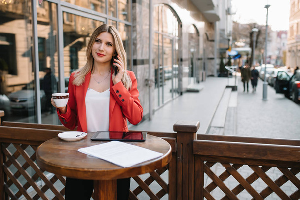 Businesswoman taking a coffee break and using smartphone. - Foto, afbeelding