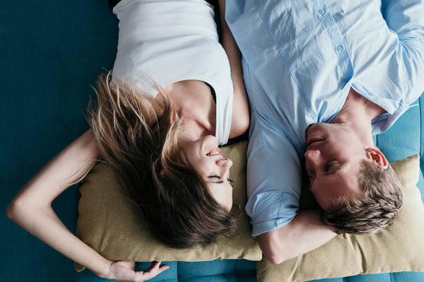 ζευγάρι ψάχνει σε φωτογραφική μηχανή και χαμογελαστός ξαπλωμένοι στο κρεβάτι - Φωτογραφία, εικόνα