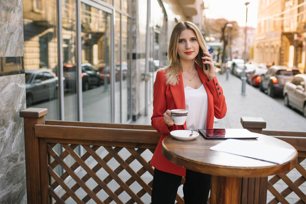 Businesswoman taking a coffee break and using smartphone. - Foto, afbeelding