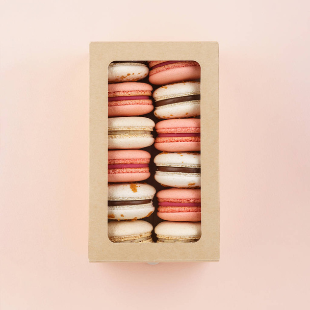 Colorful macarons in a gift box on pink background. Top view. - Foto, afbeelding
