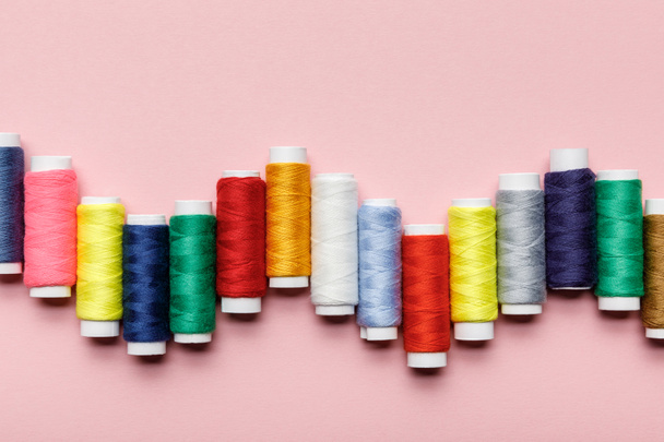 top view of arranged colorful thread coils on pink - Photo, Image