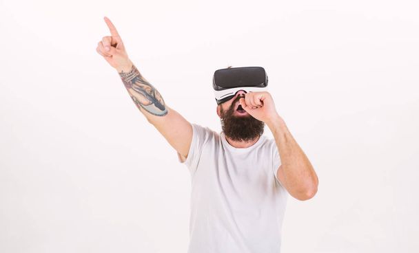 Hipster on busy face use modern technologies for entertainment or education. Man with beard in VR glasses, white background. Guy with VR glasses singing with virtual microphone. VR musician concept - Zdjęcie, obraz