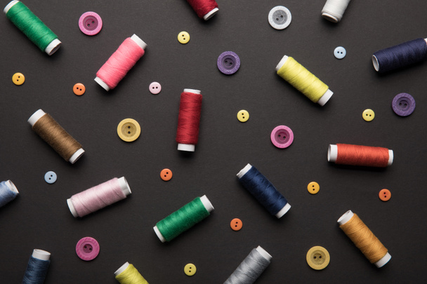 top view of colorful thread coils with various buttons isolated on black - Foto, Imagen