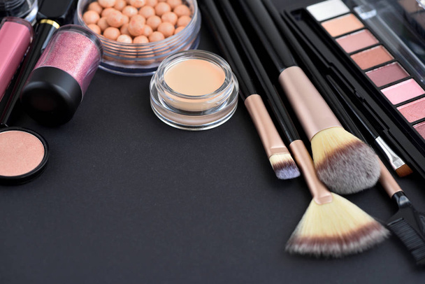 Cepillo de maquillaje y cosméticos decorativos sobre fondo negro
 - Foto, imagen