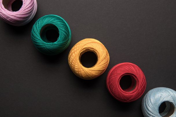 top view of arranged colorful balls of knitting yarn isolated on black - Foto, immagini
