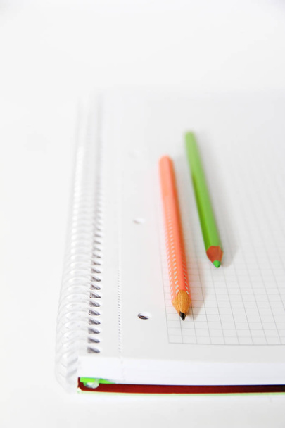 πολύχρωμα μολύβια πορτοκαλί πράσινο γκρι σε ένα λευκό σημειωματάριο φόντο - Φωτογραφία, εικόνα