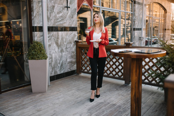 Outdoor city fashion portrait of young businesswoman working at cafe on terrace at sunny day, casual stylish outfit, mint details, using her tablet, cafe break, business concept. - Foto, Imagen