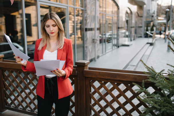 Portrait of business women in feeling of concentrate stress and see stand and hold the paper file sheet in the outdoor pedestrian walk way with the city space of exterior modern facade building - Photo, image