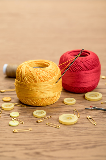 bolas de fio de tricô de algodão com botões de roupa e alfinetes de segurança na mesa de madeira
 - Foto, Imagem