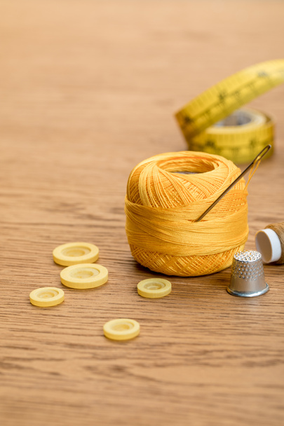 pamut kötés fonal labdát ruházati gombokkal és a hüvelyes a fa asztalra - Fotó, kép