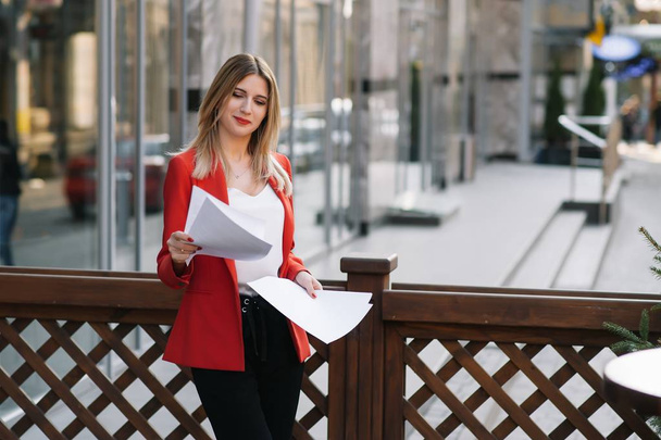 Portrait of business women in feeling of concentrate stress and see stand and hold the paper file sheet in the outdoor pedestrian walk way with the city space of exterior modern facade building - Foto, imagen