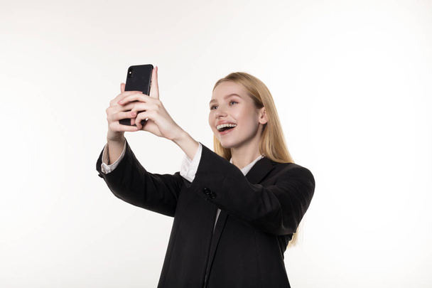 Taillenhoch Porträt einer lächelnden blonden Geschäftsfrau, die ein Selfie mit ihrem Handy macht - Foto, Bild