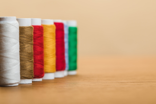 bobines de fil de coton coloré en rangée isolé sur beige avec espace de copie
 - Photo, image