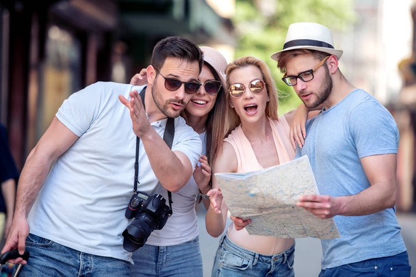 Felices turistas alegres tratan de encontrar destino en el mapa de la ciudad
. - Foto, imagen
