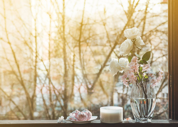 Cozy spring still life: cup of hot tea with spring bouquet of flowers on vintage windowsill with a pink marshmallow - Foto, afbeelding