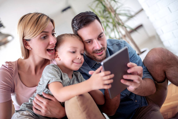 Família desfrutando junto com tablet em casa
. - Foto, Imagem