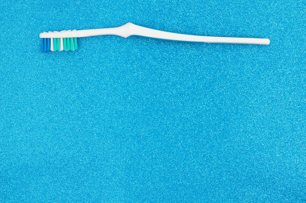 Зубна щітка на синьому блискучому фоні
 - Фото, зображення