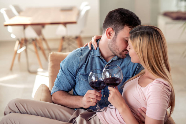 Piękna szczęśliwa para spędza romantyczny dzień razem w domu, picie wina. - Zdjęcie, obraz