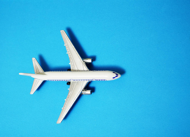 metal toy - airplane  on blue paper background. modern plane isolated on blue backdrop. t - Foto, Imagen