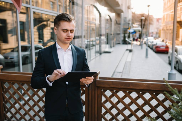 Молодой бизнесмен с планшетом рядом с современным зданием
. - Фото, изображение