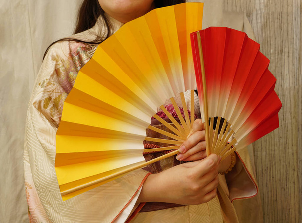 female hands with two colorful fans. Japanese woman in a kimono - Foto, Bild
