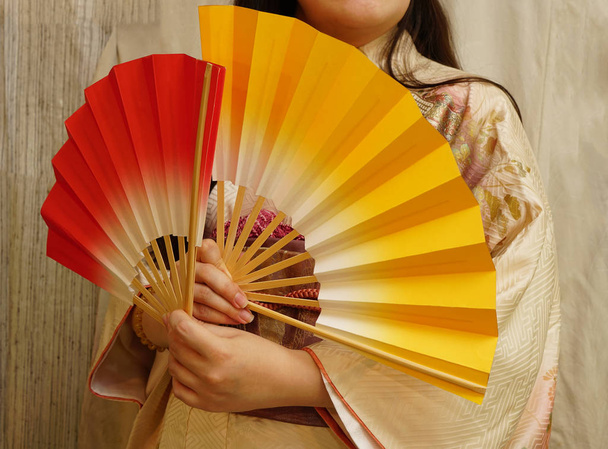 female hands with two colorful fans. Japanese woman in a kimono - Фото, изображение