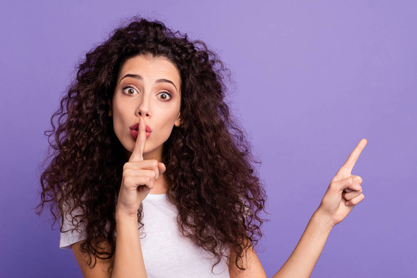 Close up photo beautiful funny her she lady arm index finger indicate empty space advise product hand lips ask stop talk tell speak wear casual white t-shirt clothes isolated violet purple background - 写真・画像