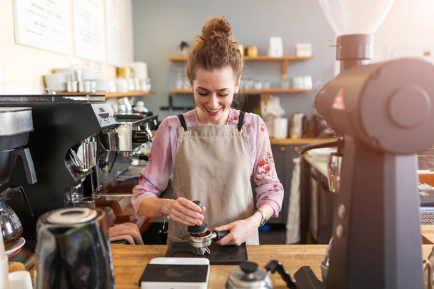 junge Barista bereitet Kaffee für Kunden an ihrem Café-Tresen zu - Foto, Bild