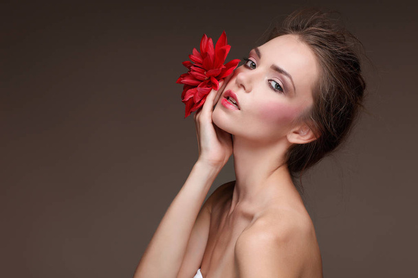 Beautiful  girl, isolated on a dark - grey  background with red flowers, emotions, cosmetics - Φωτογραφία, εικόνα