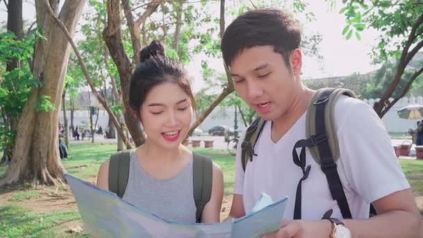 Traveler Asian couple direction on location map in Bangkok, Thailand, sweet Asia couple looking on map find landmark while spending holiday trip. Lifestyle couple travel in city concept. - Footage, Video