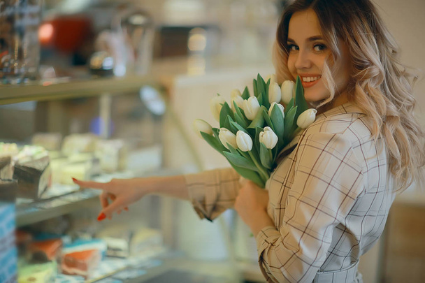 girl with a bouquet of flowers in a cafe / beautiful showcase, diet, happiness, mood - Valokuva, kuva