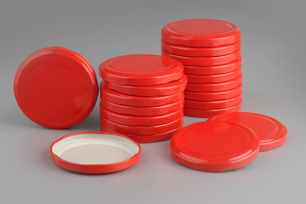 Schroef doppen voor glazen potten. Voor conserven, ingeblikt voedsel. Rode doppen op grijze achtergrond - Foto, afbeelding