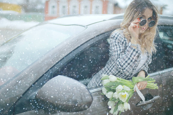 spring snowfall beautiful girl with flowers / concept of international women's day march, gift for girlfriend, happiness - Photo, Image