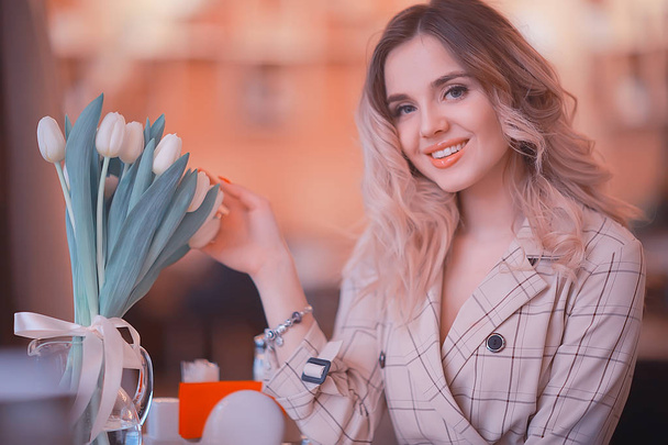 fille assise dans un café à une table / beau jeune modèle posant avec un bouquet de fleurs, heureuse petite amie adulte
 - Photo, image