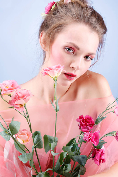 Beautiful  girl, isolated on a blue  background with varicoloured flowers, emotions, cosmetics - Foto, afbeelding