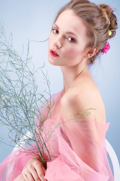 Beautiful  girl, isolated on a blue  background with varicoloured flowers, emotions, cosmetics - 写真・画像